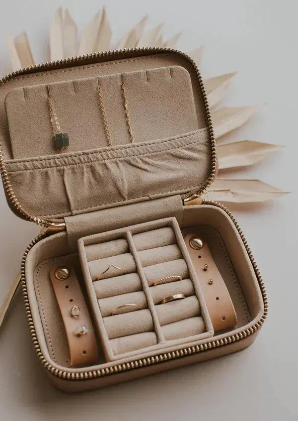 Beige velvet travel jewelry organizer with rings, necklaces, and earrings in compartments