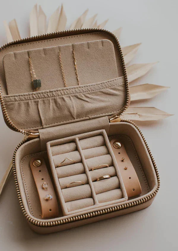 Beige velvet travel jewelry organizer with rings, necklaces, and earrings in compartments