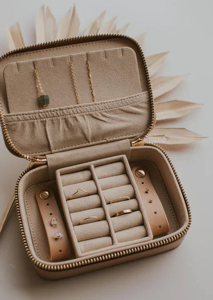 Beige velvet travel jewelry organizer with rings, necklaces, and earrings in compartments