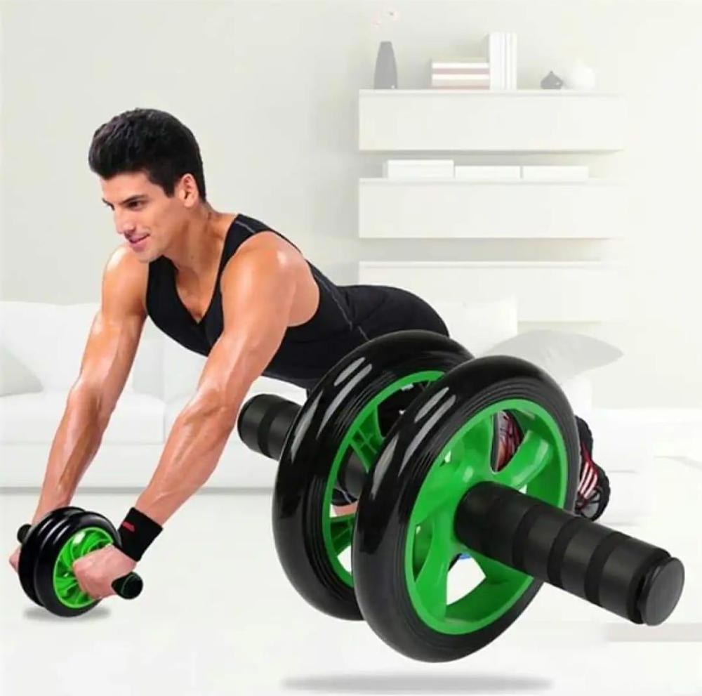 Man using green and black ab roller wheel for core workout at home
