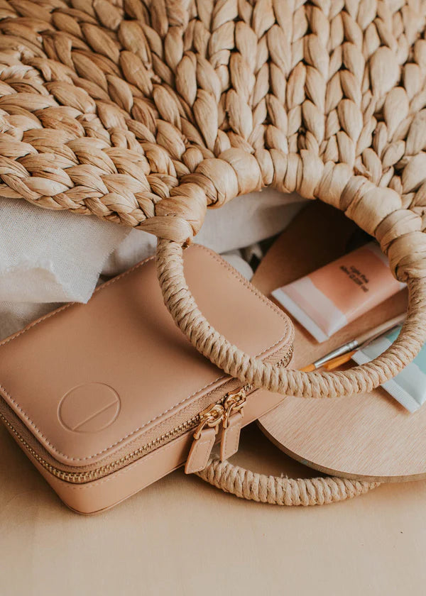 Woven straw tote bag with beige leather pouch and makeup essentials, perfect for summer outings
